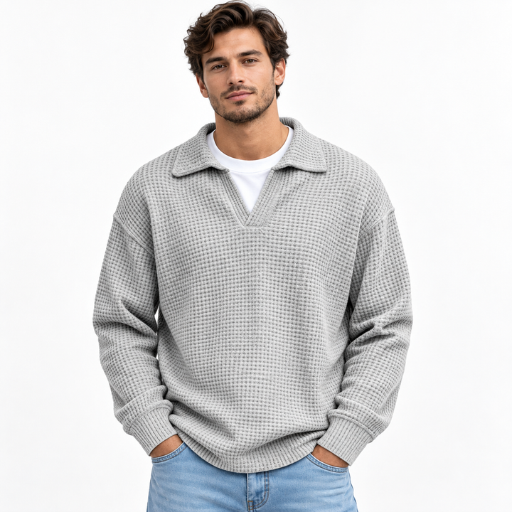 Gray waffle knit polo for men with long sleeves, open lapel collar and loose-fit silhouette, shown from the front on a model.
