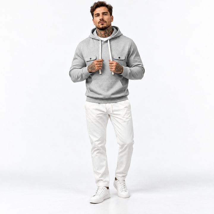 Front view of male model holding drawstrings of a gray multi-pocket hoodie