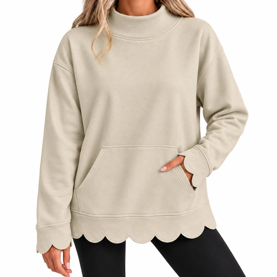 Close-up of the sand beige pullover showing a front kangaroo pocket, fine stitching, scalloped hem and scalloped sleeve ends.