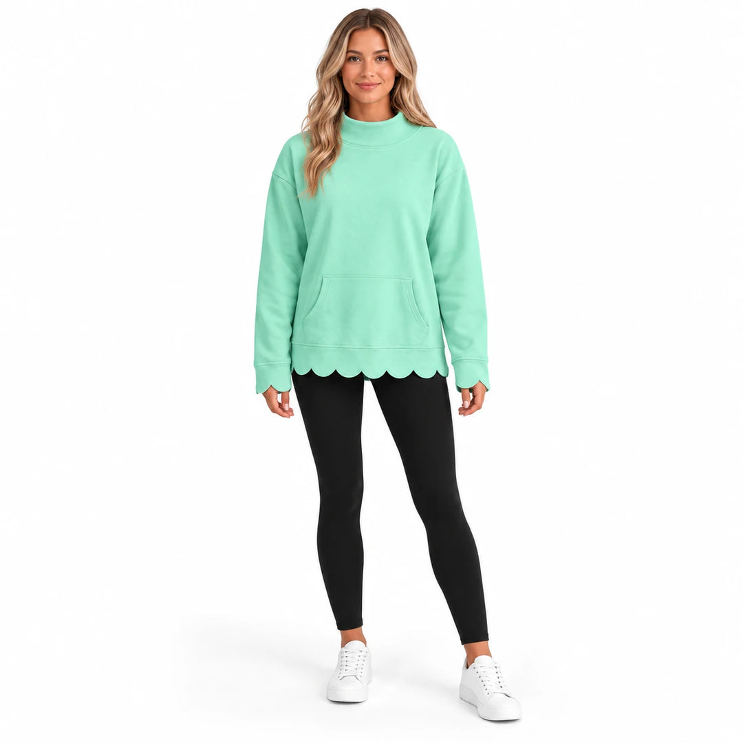Full-body model wearing a mint green pullover with a mock collar, front pocket and scalloped edges with leggings and sneakers