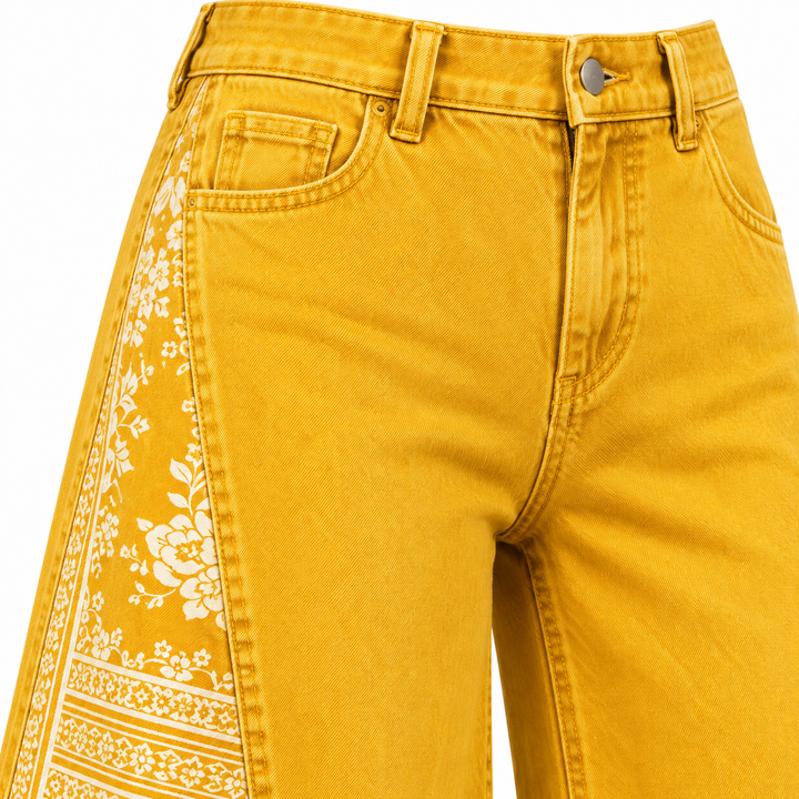 Mustard yellow pants close-up showing waistband, pocket, stitching and printed side panel