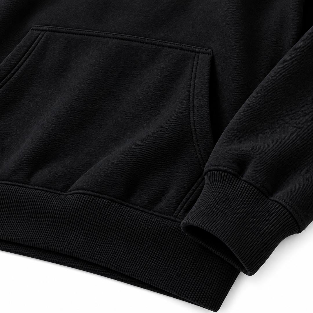 Close-up of the black hoodie kangaroo pocket and ribbed cuff, with the fabric and stitching visible against a white backdrop.
