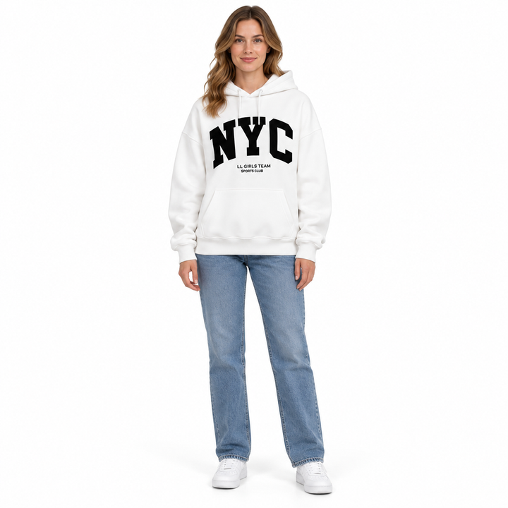 Full body model in a white hoodie with NYC graphic print, long sleeves, jeans and sneakers against a white studio background.