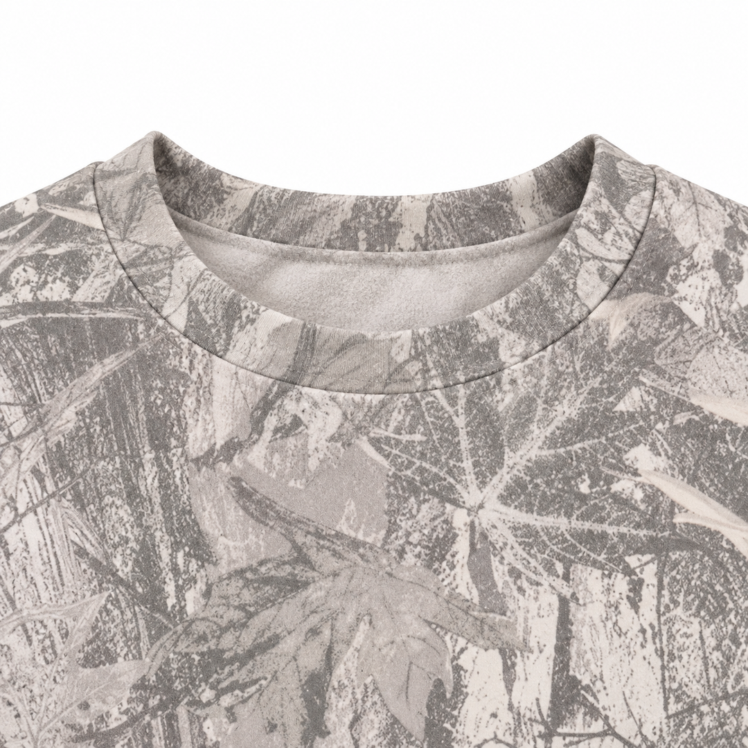 Close-up of the grey printed sweatshirt neckline, showing a crew neck edge and branch pattern against a plain white backdrop.