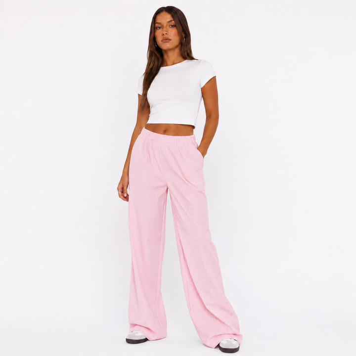 Pink striped wide leg pants for women on a studio model, showing elastic waist, vertical stripes and relaxed Y2K silhouette.