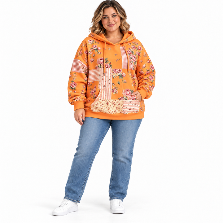 Plus size floral hoodie in tangerine on a model with blue jeans and white sneakers, full-length front view