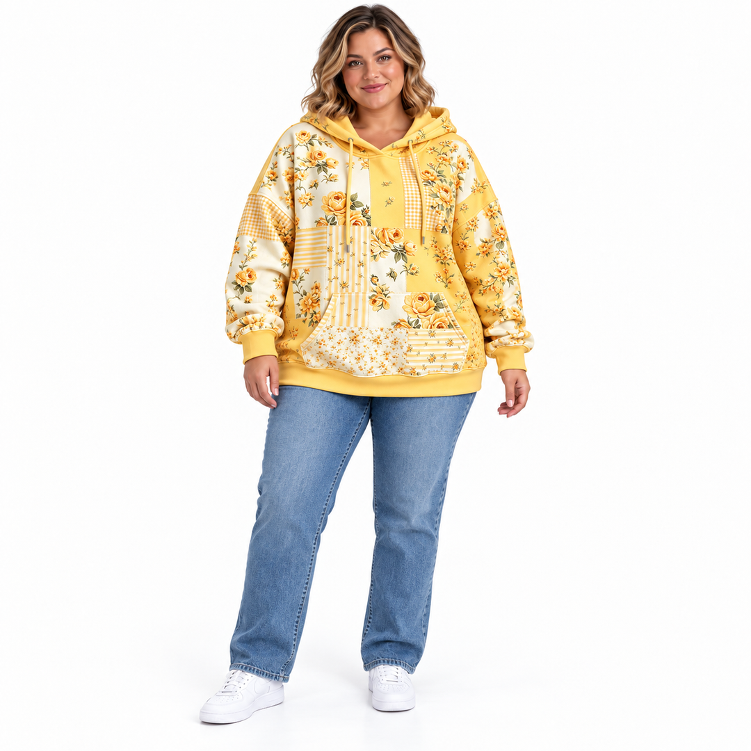 Plus size floral hoodie in yellow on a model wearing blue jeans and white sneakers, full-length studio view