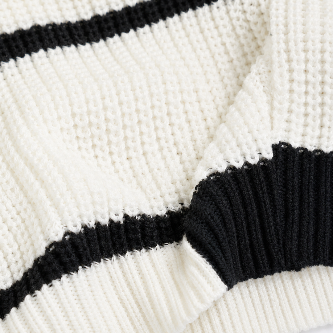 Close-up of the white sweater knit showing the textured stitch pattern, black stripe edge, and ribbed finish in sharp detail.