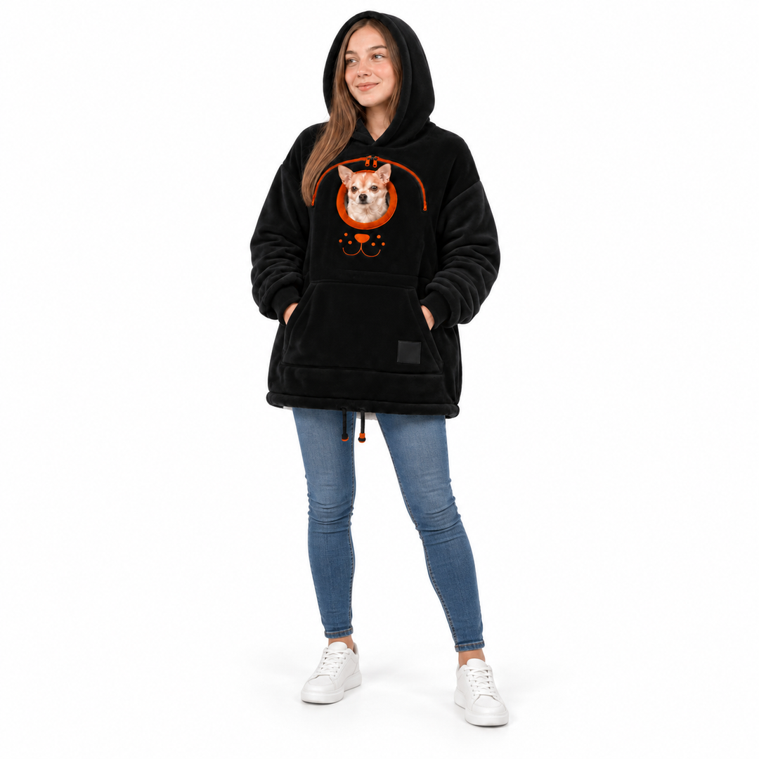 Woman wearing a black hooded pullover with a real small dog, front pocket and hem drawstrings against a plain white backdrop.