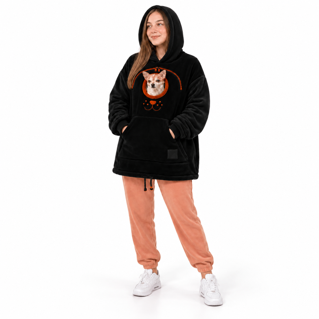 Woman wearing a black hooded pullover with a real small dog, front pocket and hem drawstrings against a plain white backdrop.
