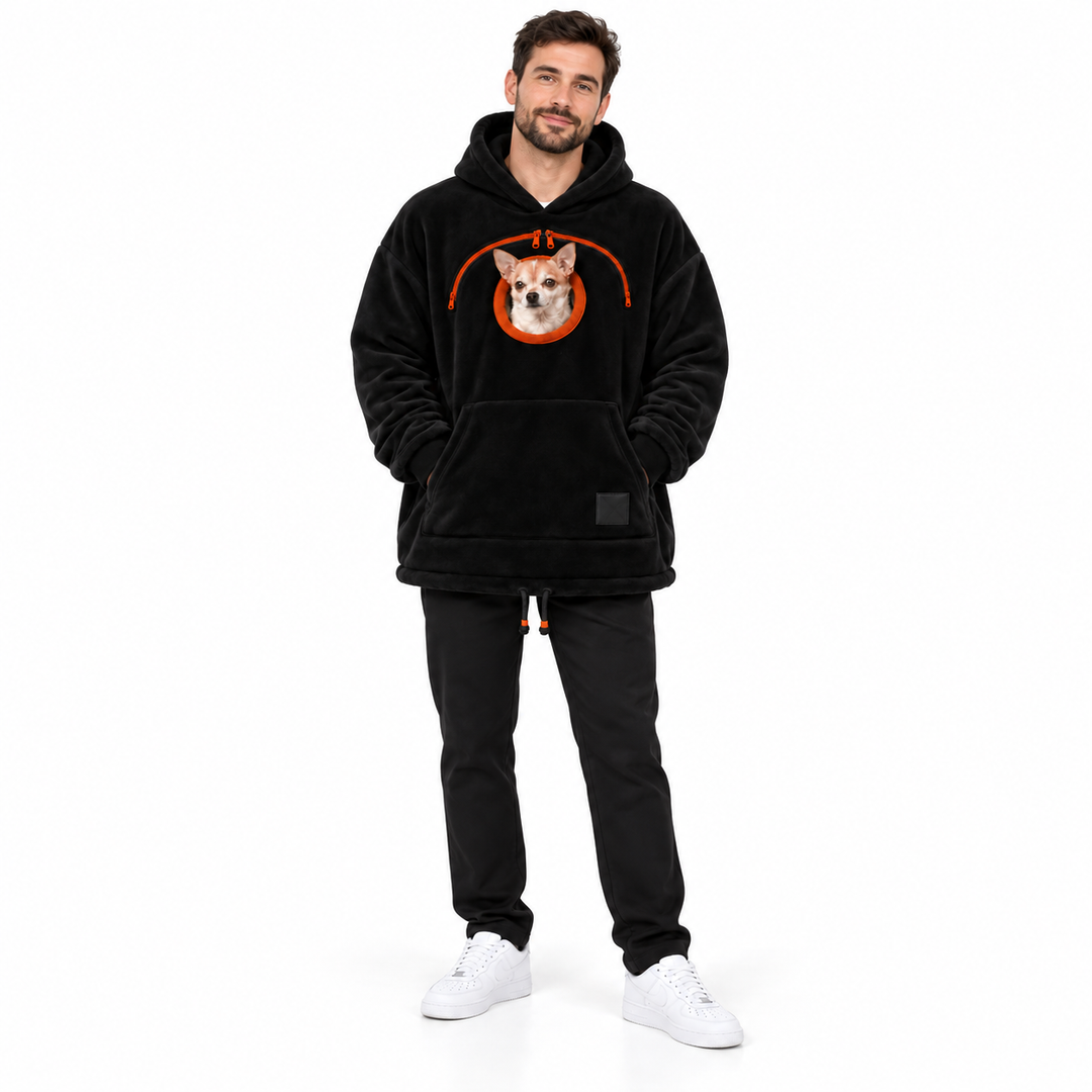 Man wearing the black plush hoodie with an orange chest zipper, dog and a front pocket on a seamless white studio background.