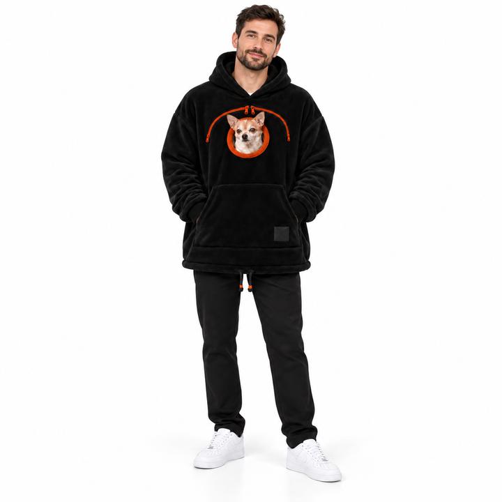 Man wearing the black plush hoodie with an orange chest zipper, dog and a front pocket on a seamless white studio background.