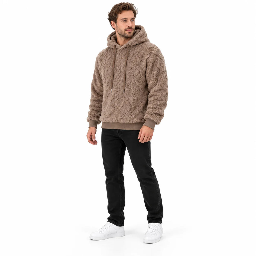 Camel brown pullover shown at a three-quarter angle on a male model, displaying the hood, geometric texture and ribbed cuffs.