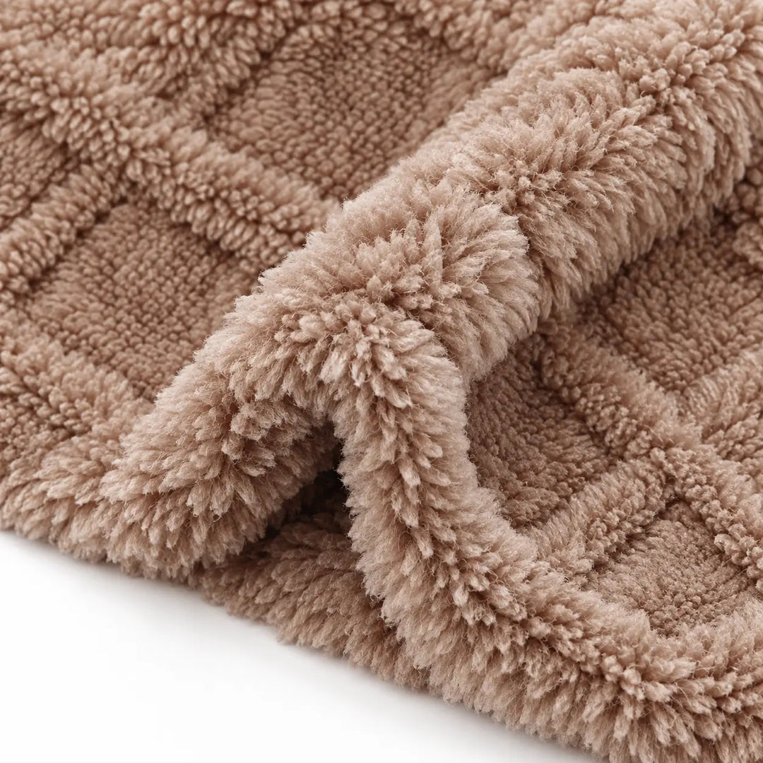 Close-up of camel brown plush fabric with a soft fold, revealing the raised diamond pattern and the surface texture on white.