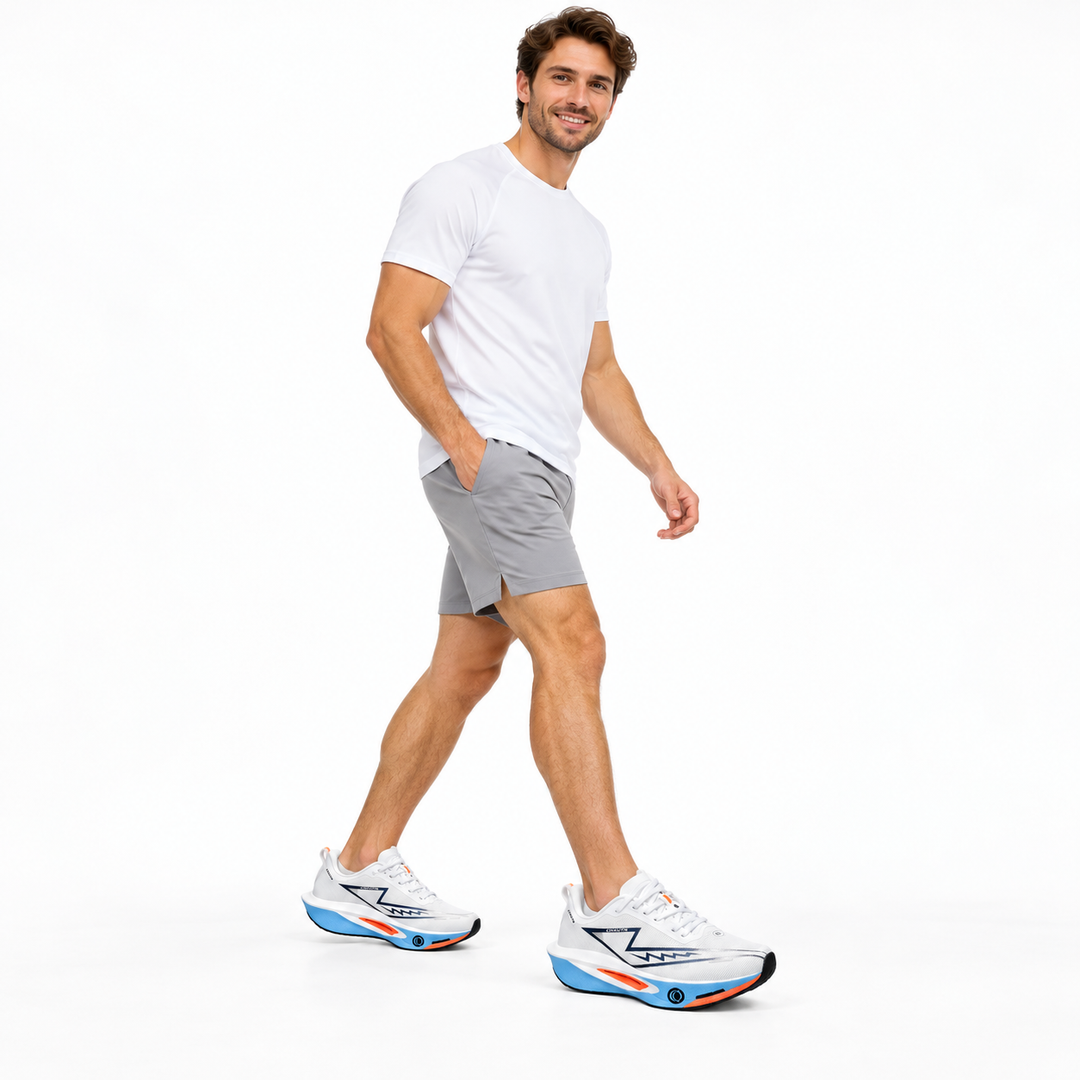 Male model wearing white and blue lace-up sneakers on a white studio background.