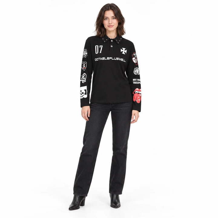 Full-length female model wearing this black printed long sleeve polo with charcoal jeans and black boots on a white backdrop.