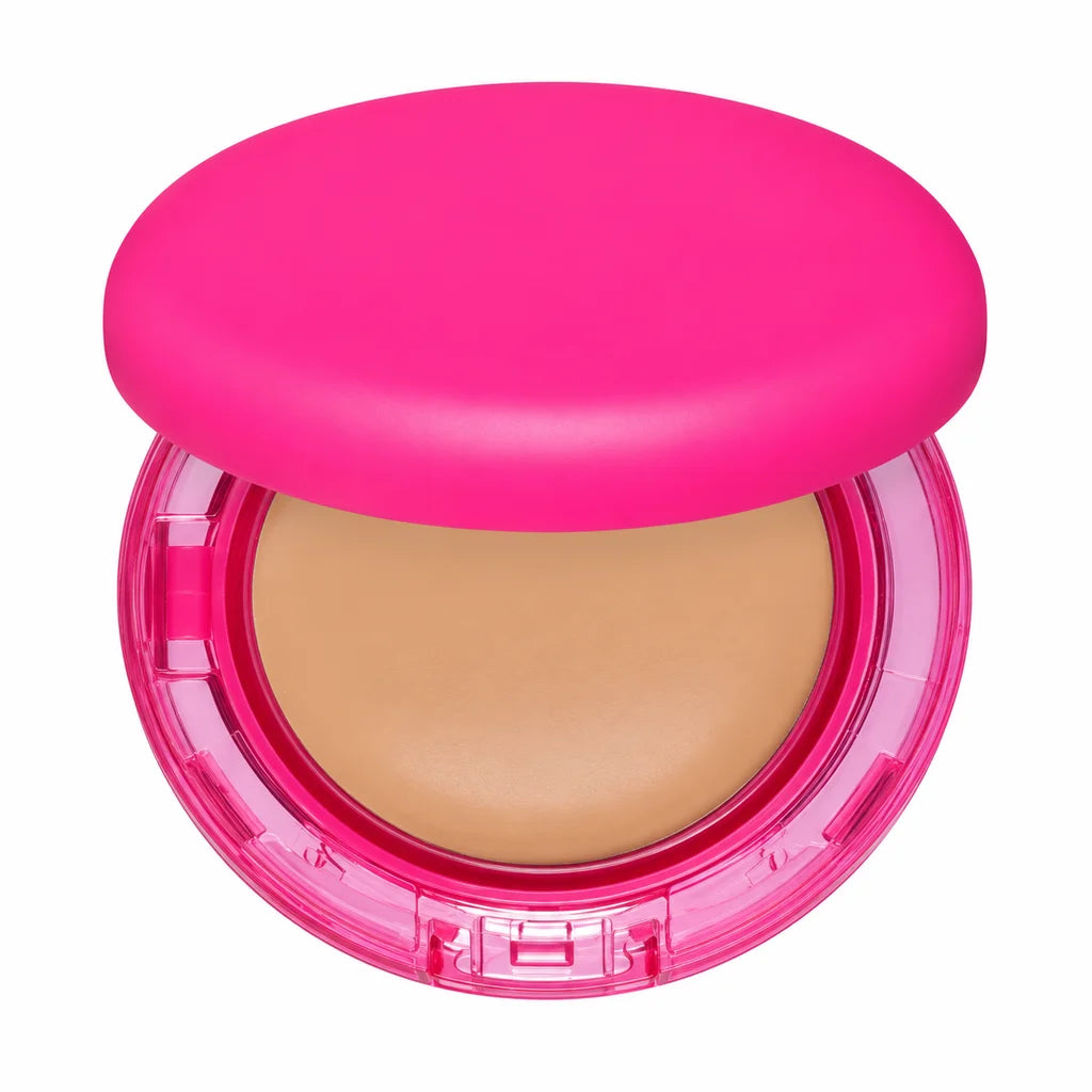 Detail view of the pink foundation compact showing the beige pan, transparent case, front clasp and rounded lid on pure white