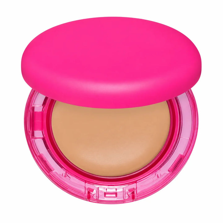 Detail view of the pink foundation compact showing the beige pan, transparent case, front clasp and rounded lid on pure white