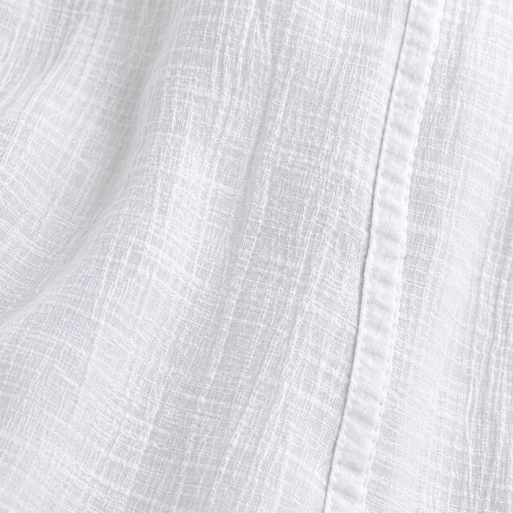 Close-up of the White trousers crinkle fabric texture and nearby leg seam