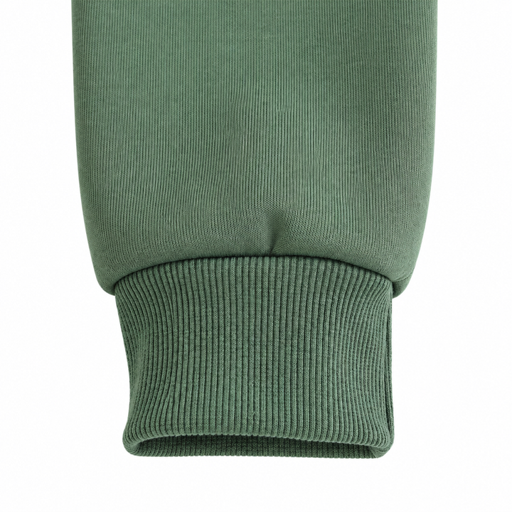 Close-up of the olive green sweatshirt sleeve cuff, showing ribbing, stitching and fabric folds against clean white backdrop.