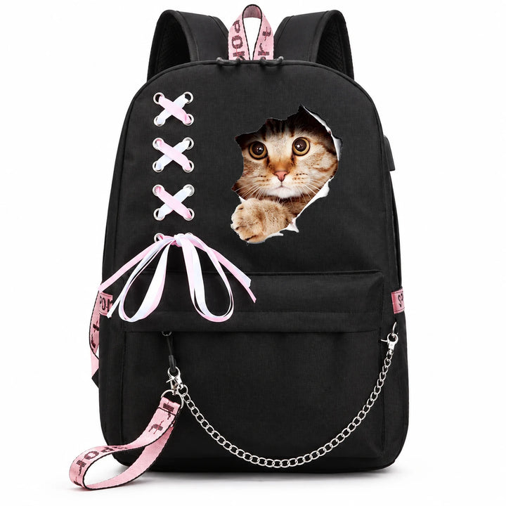 Black backpack with a wide-eyed tabby head and paw print, pink-and-white ribbon lacing, bow and draped silver chain on white.
