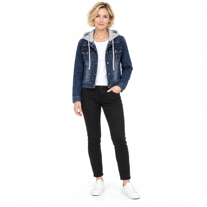 Front view of a blonde model in a dark blue denim jacket with grey hood, pale drawstrings, black trousers and white sneakers.