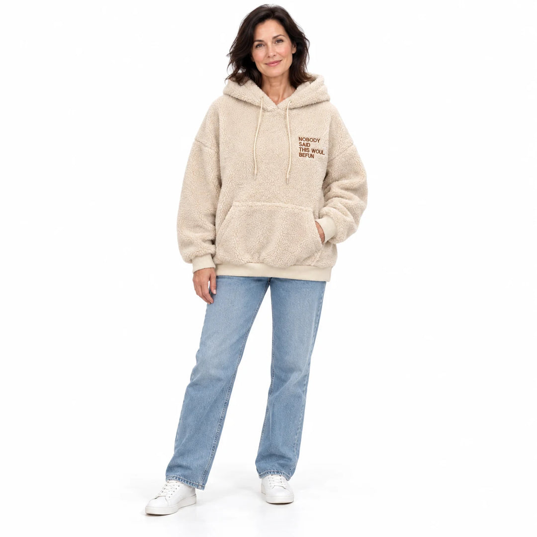 Apricot fleece pullover worn by an adult woman, showing the fleece texture and chest lettering, on a white studio background.