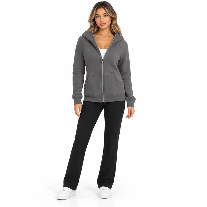 Studio model wearing the Charcoal Gray zip hoodie, showing front pockets, ribbed cuffs and hem, on white with black trousers.