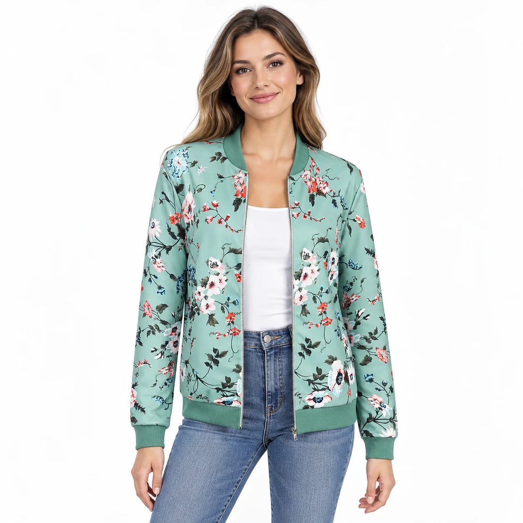 Model wearing the Green printed jacket over a white top and blue jeans showing flowers, a front zipper and green ribbed trim.