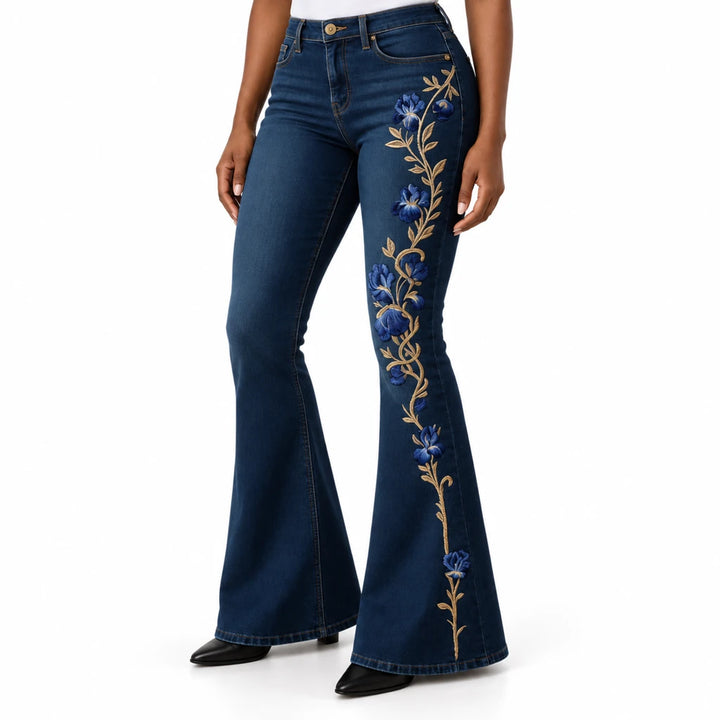 Close view of dark blue floral flare jeans showing the waist, slim upper leg, blue flower print and flared hem.