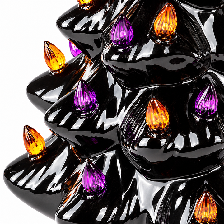 Close-up of shining black Halloween tree tiers with purple and amber teardrop details, photographed against a white backdrop.