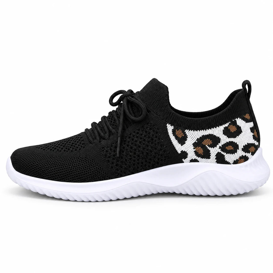 Side view of a black mesh lace-up sneaker with a white sole and tan leopard heel panel, photographed against a white setting.