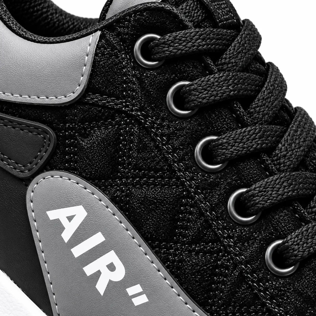 Close-up of Black and Gray sneaker laces and eyelets with gray collar edge, patterned black upper and partial AIR side panel.