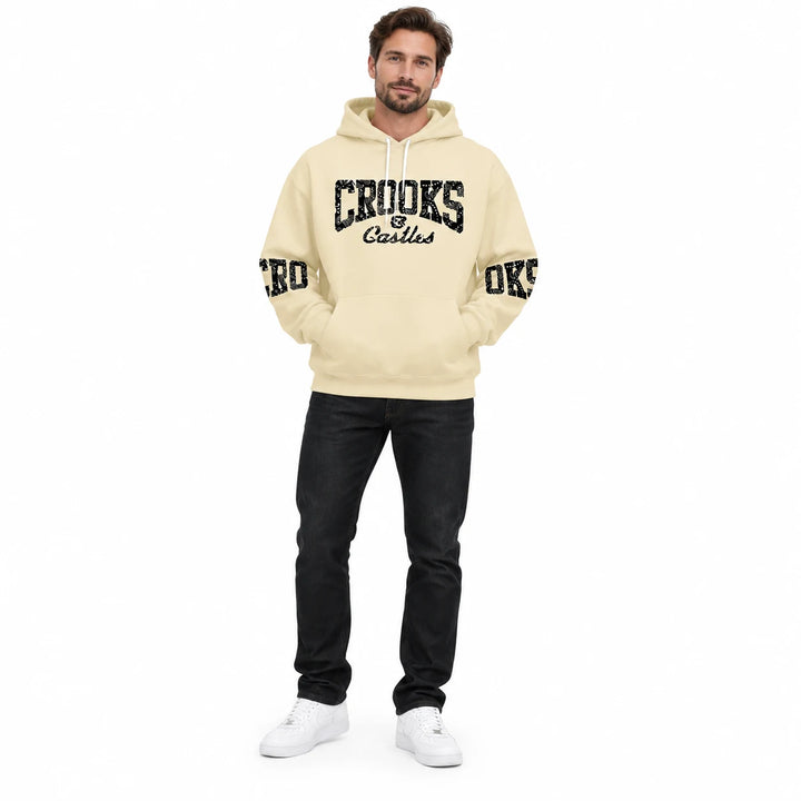 Full-length male model wearing a Cream graphic hoodie with chest and sleeve prints on a white studio background
