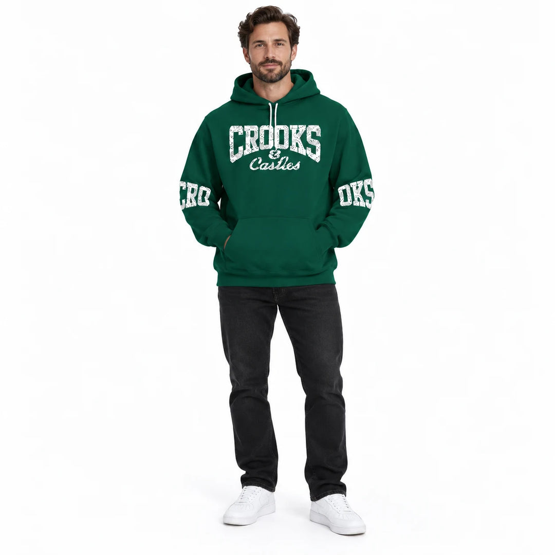Full-length male model wearing a Forest Green graphic hoodie with chest and sleeve prints on a white studio background