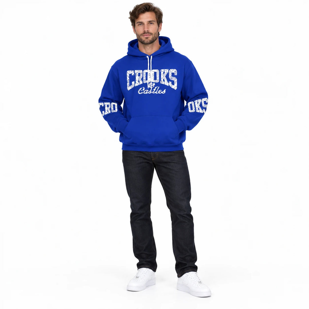 Full-length male model wearing a Royal Blue graphic hoodie with chest and sleeve prints on a white studio background
