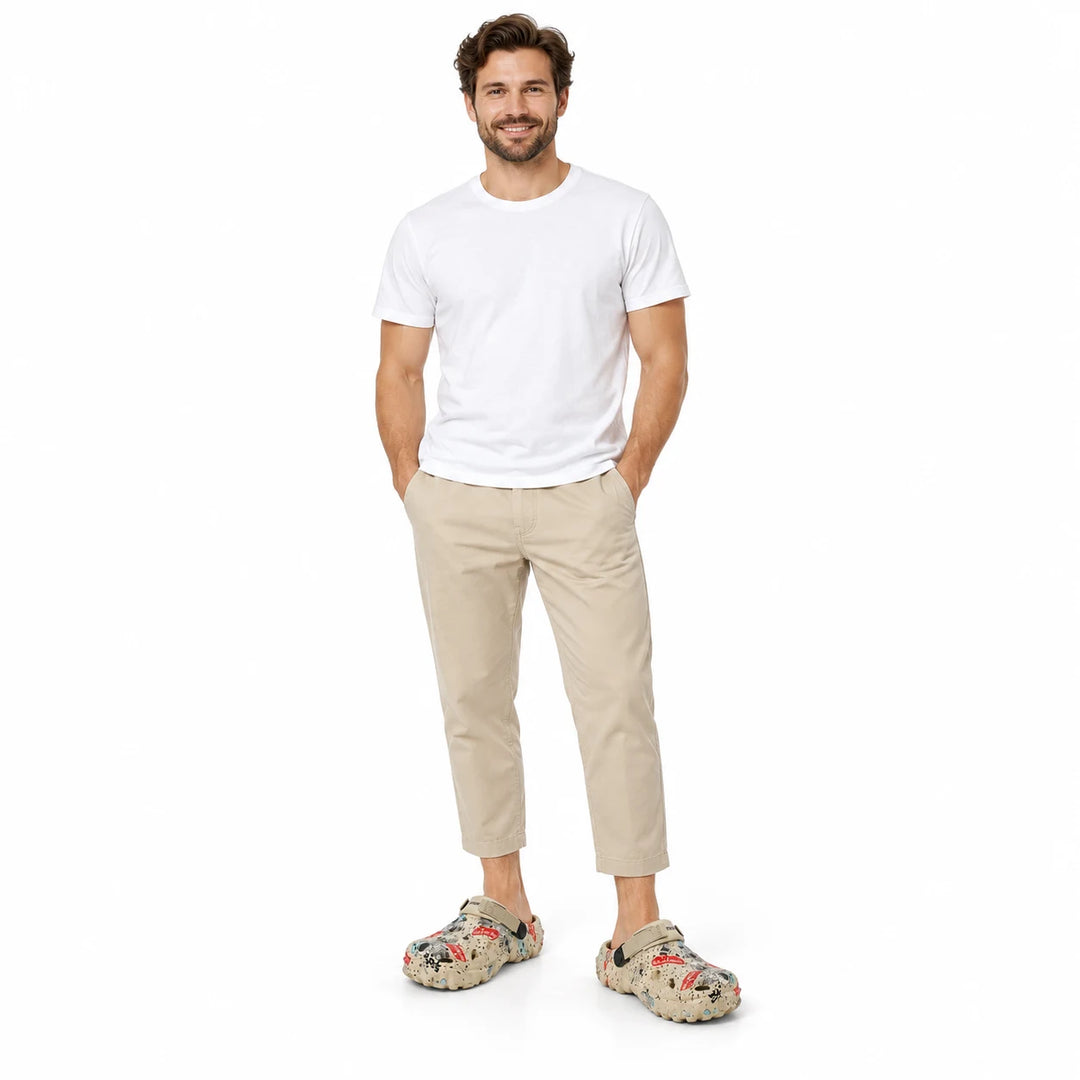Full-length male model wearing Khaki graffiti garden clogs on a white studio background