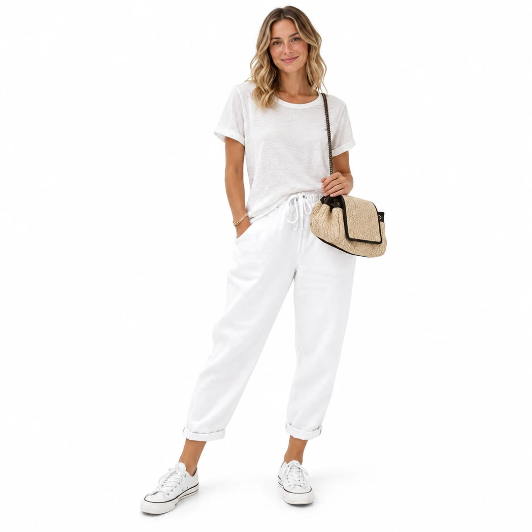 White drawstring ankle pants on a standing adult woman, showing the ankle length and drawstring, on a plain white background.