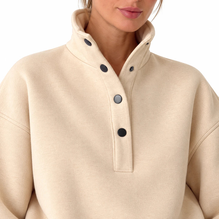 Close-up of the beige stand collar and dark buttons on the pullover, showing visible exterior details, on a white background.