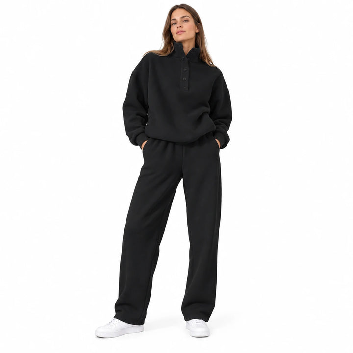 Black matching set with a stand collar and dark buttons, worn by an adult model in a front view on a white studio background.