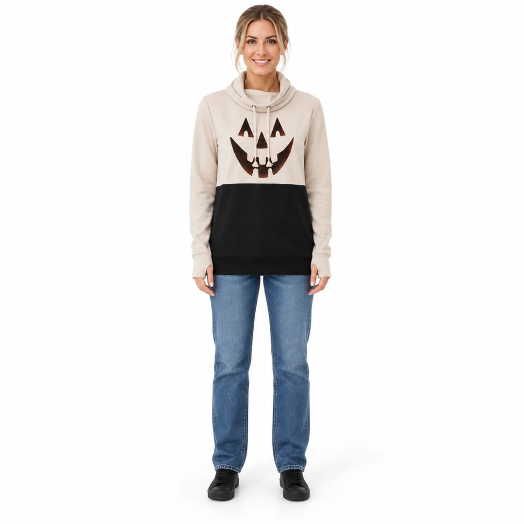 Woman wearing a beige and black pumpkin top with jeans and black shoes, shown in a full-body front view against a white wall.