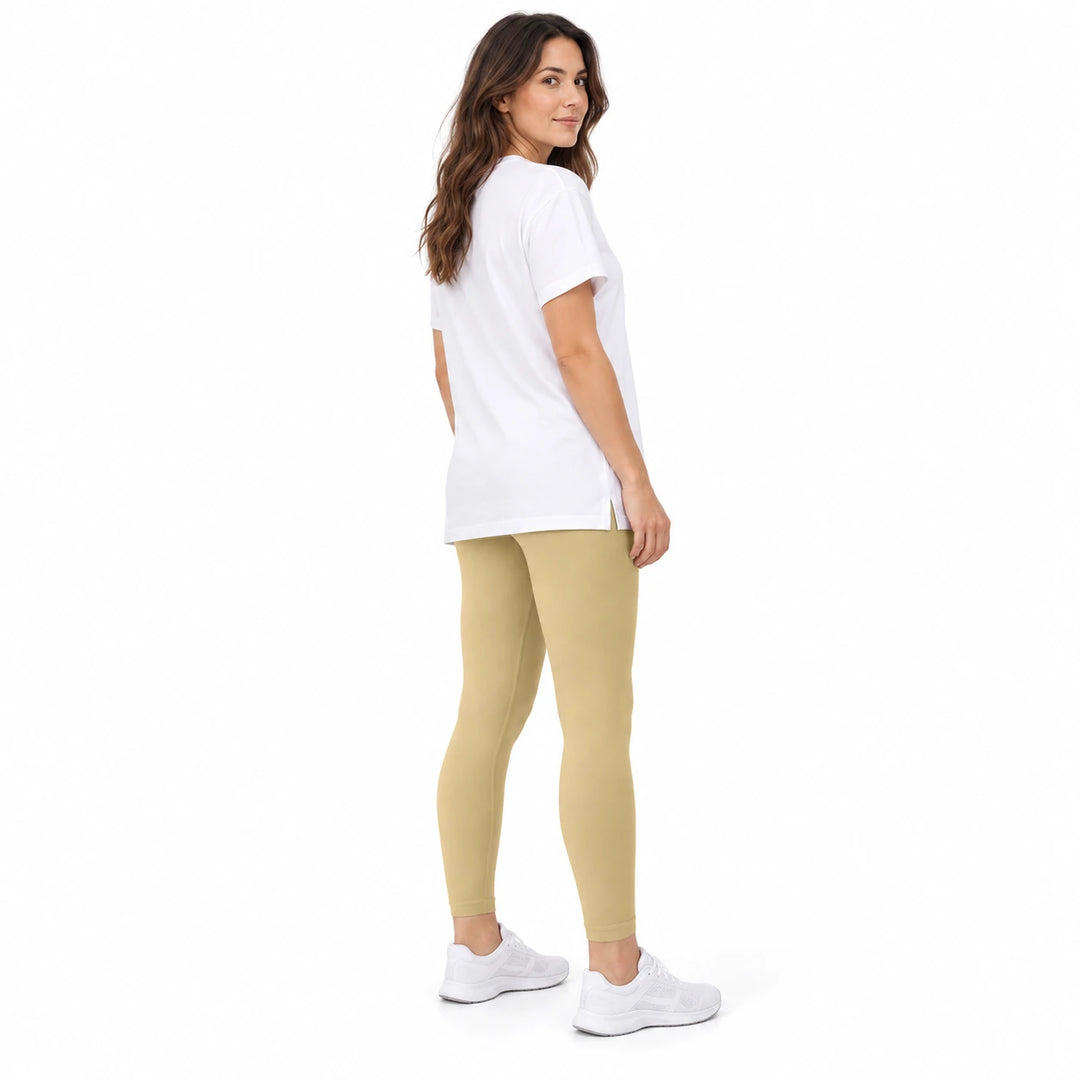 Adult model in Alpaca contoured leggings, a white longline T-shirt and white trainers, standing on a white studio background.