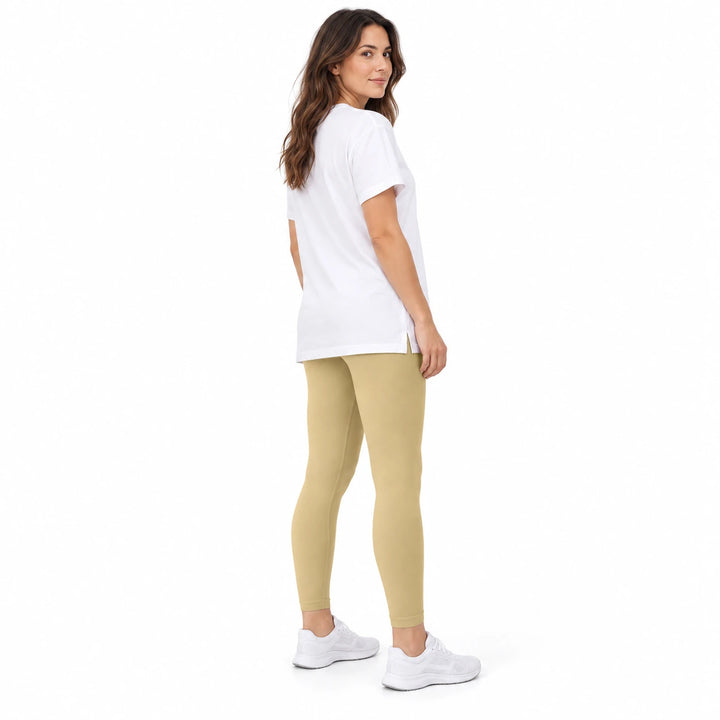 Adult model in Alpaca contoured leggings, a white longline T-shirt and white trainers, standing on a white studio background.