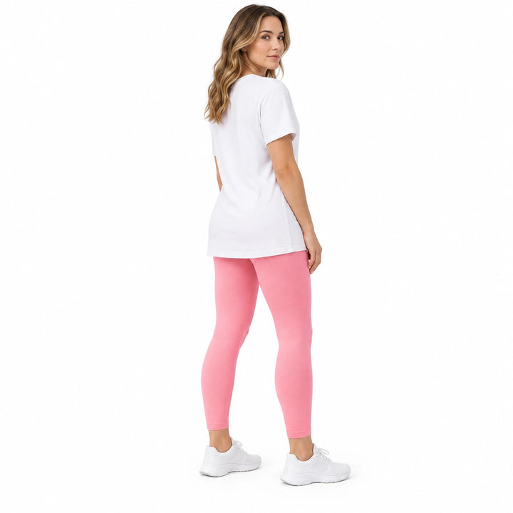 Adult model in Peach Powder high-waisted leggings, white longline T-shirt and white sneakers on a pure white studio backdrop.