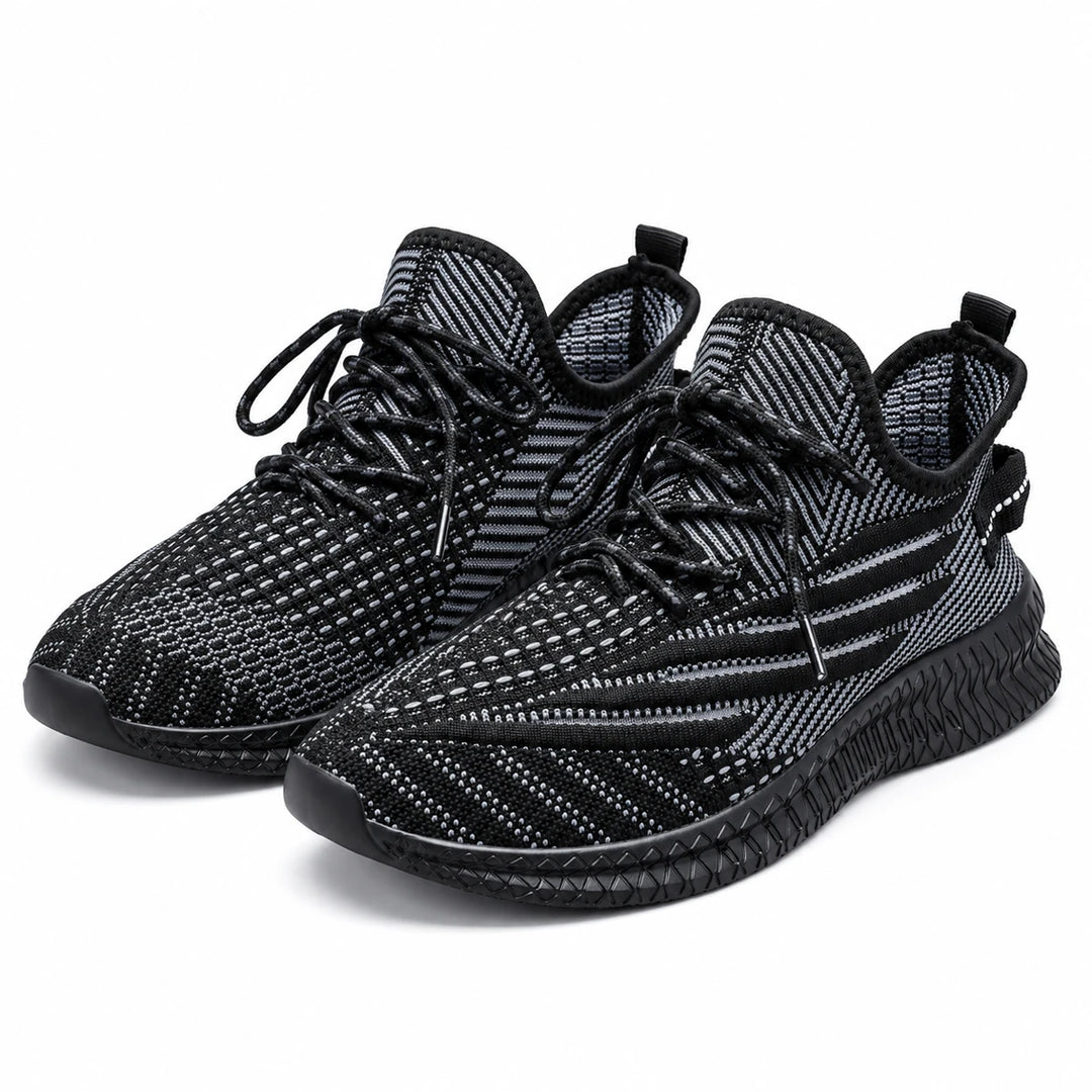Black mesh sneakers shown as a pair from the front, with laces &amp; patterned toe boxes visible in a studio photograph on white.