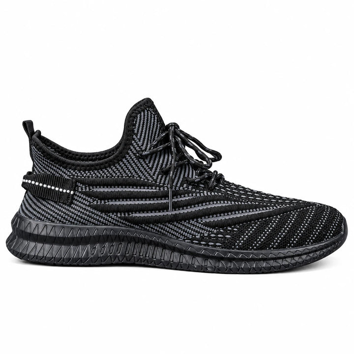 Black mesh sneaker shown in side profile, with knit stripes, black laces &amp; a ribbed outsole on a plain white studio backdrop.
