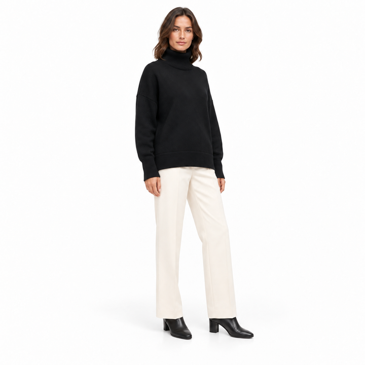 Front three-quarter view of the black turtleneck sweater on a model, with dropped shoulders, ribbed cuffs and an untucked hem