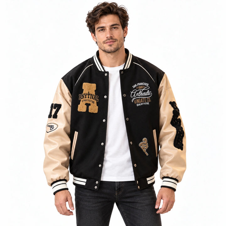 Male model wearing the Black varsity jacket with cream sleeves over a white T-shirt and jeans on a white background.