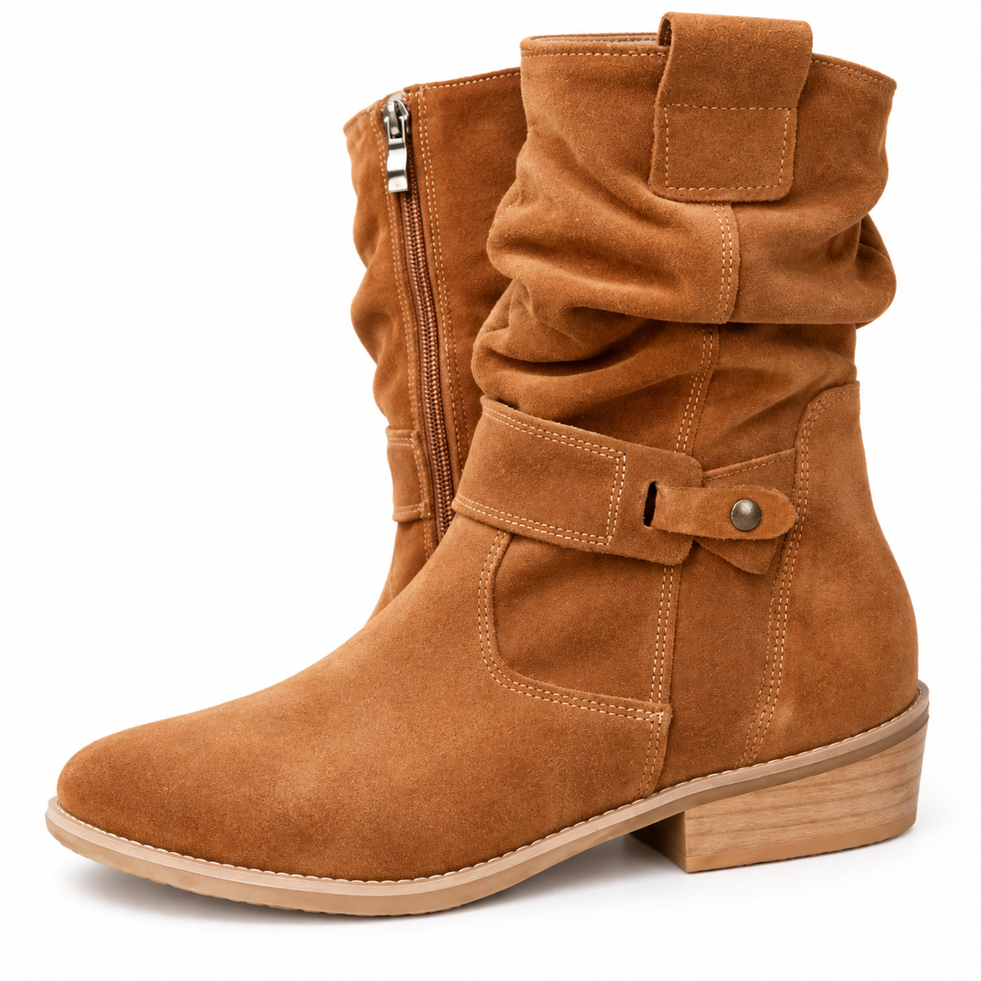 Close-up of a brown boot exterior showing its textured surface, stitching, gathered shaft and buttoned side tab in the scene.