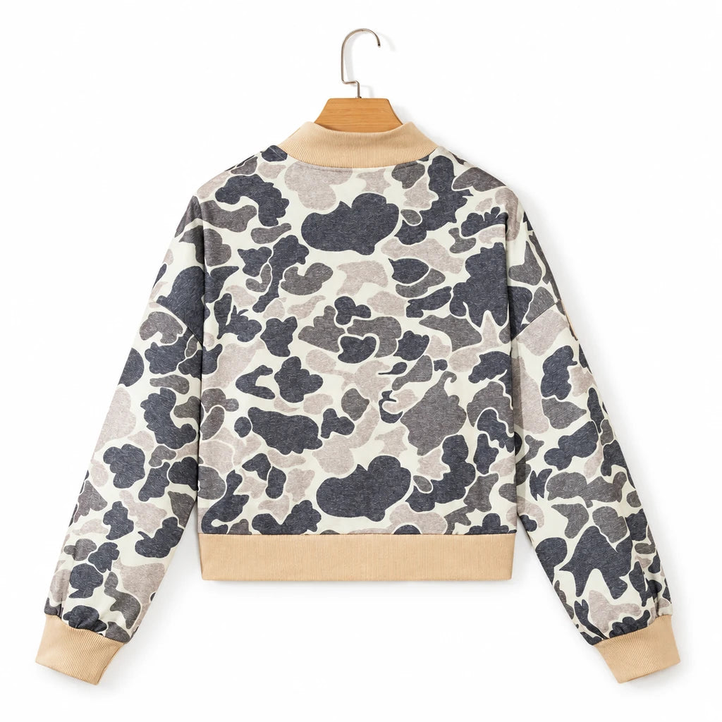 Back view of the camouflage bomber on a wooden hanger against a white backdrop, showing long sleeves and beige ribbed edging.